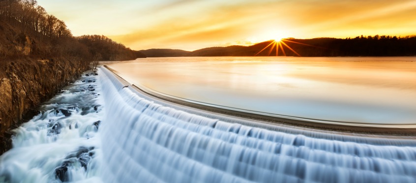 Sunset Over Flowing Waterfall Dam