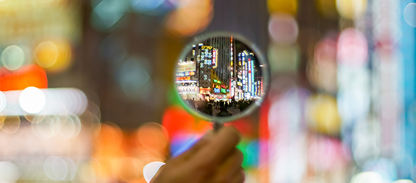 Magnifying Glass Over Blurred City Lights