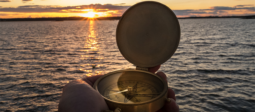 Compass Overlooking Ocean Sunset Scene